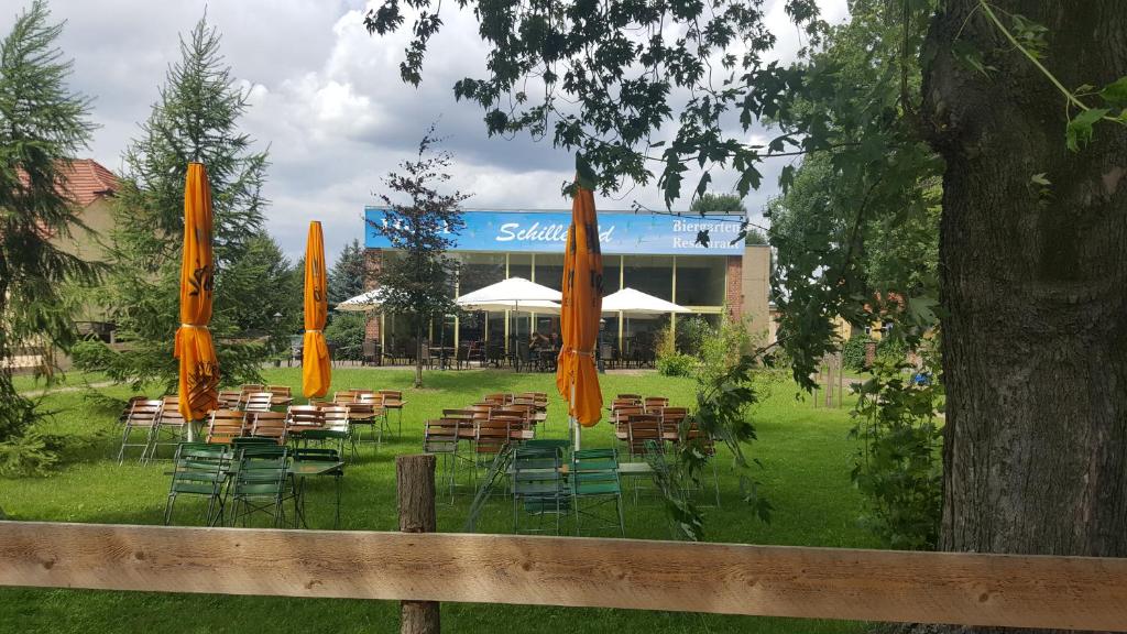 eine Gruppe von Tischen und Stühlen mit orangefarbenen Sonnenschirmen in der Unterkunft Gasthaus Schillebold in Peitz