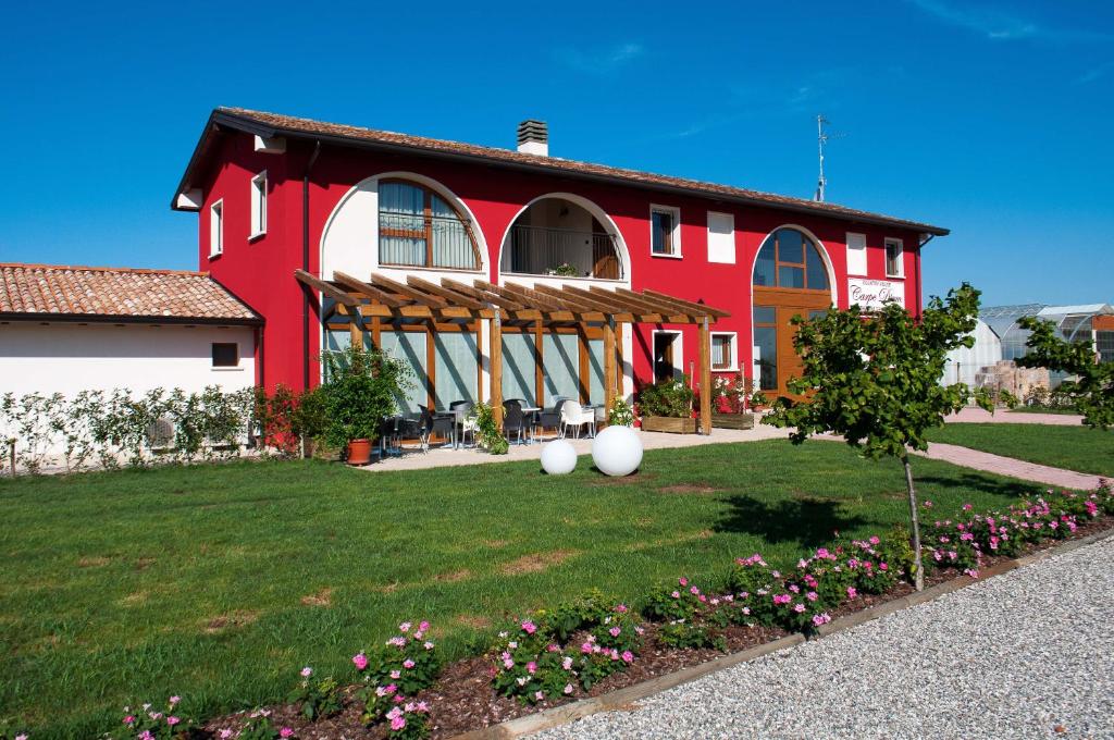 una casa roja y blanca con un patio con flores en Carpe Diem Countryhouse, en Cesarolo