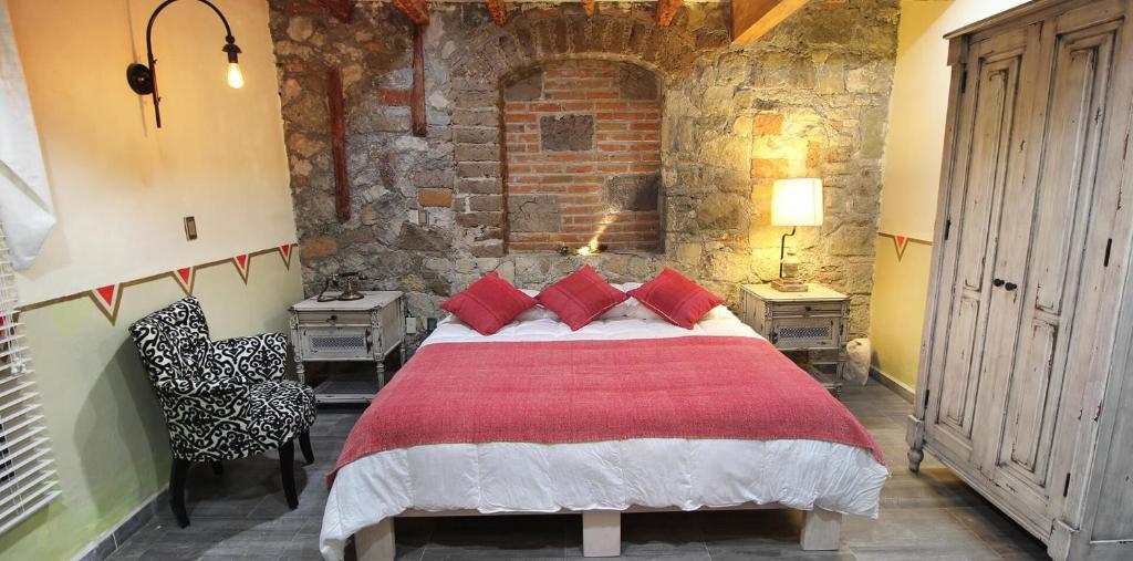 een slaapkamer met een groot bed met rode kussens bij Alondra Hotel Boutique in Mineral del Monte