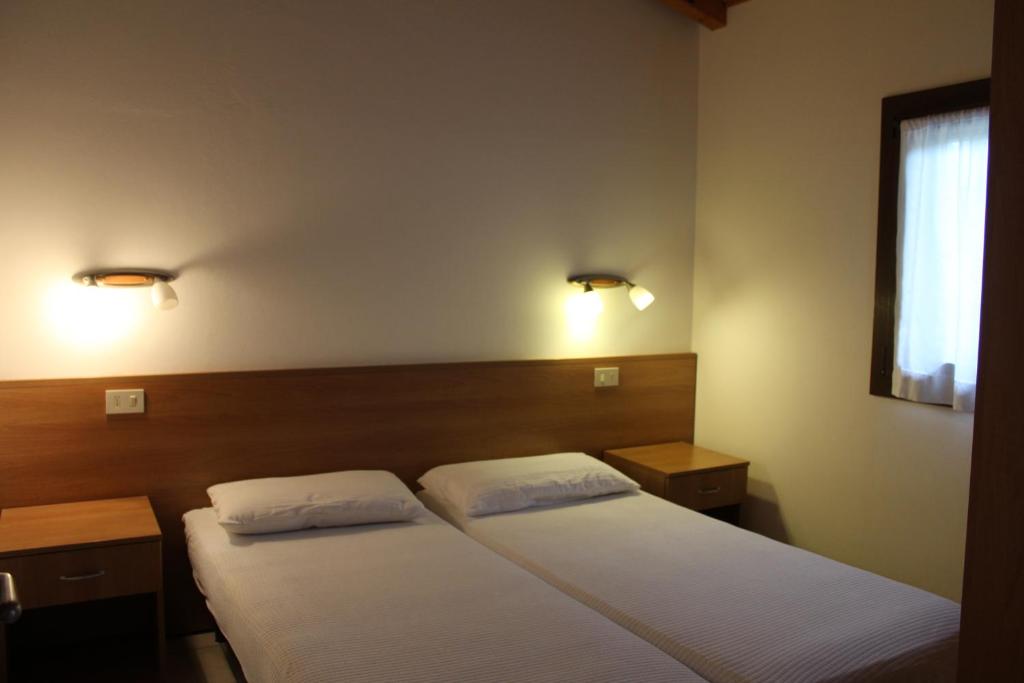 una camera con due letti e due luci sul muro di Bungalows Alloggi Angiolin Ketty a Cavallino-Treporti