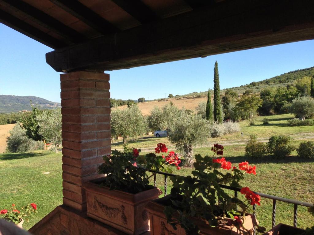 uma vista para um campo a partir de um alpendre com flores em Casale delle Due Fonti em San Venanzo