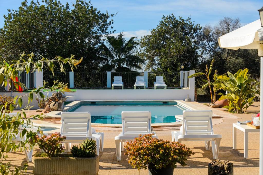 a swimming pool with white chairs and a swimming pool at Villa Can Prats in Santa Eularia des Riu