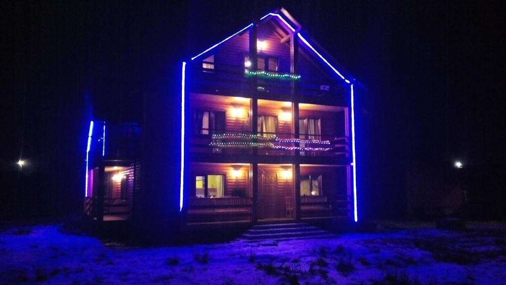 un bâtiment avec des lumières bleues allumées la nuit dans l'établissement Плай, à Verkhovyna