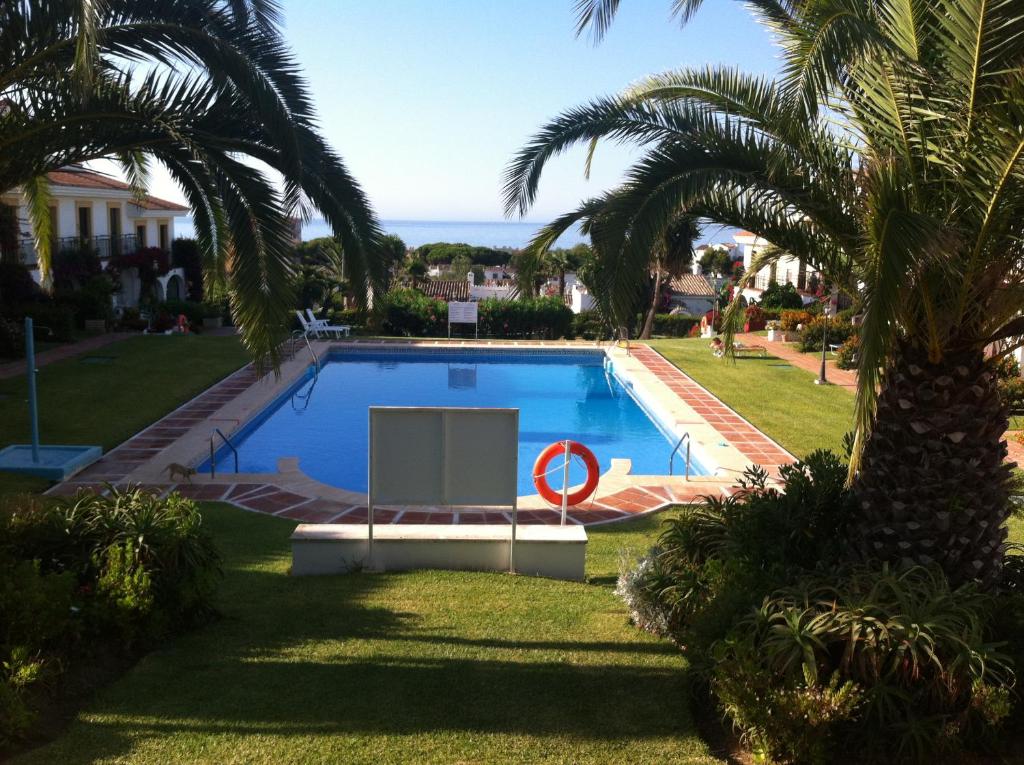 a swimming pool in a yard with a palm tree at Adosado en residencial in Mijas Costa