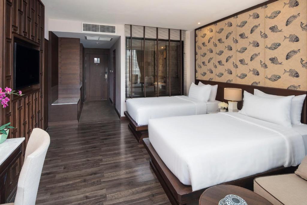 A bright room with two beds, a sofa, and dark wood flooring.