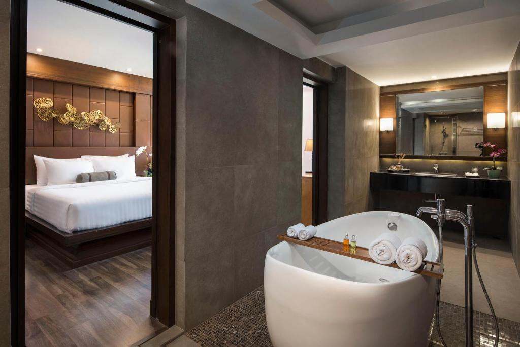 A bathroom with a freestanding soaking tub beside an open view into the bedroom.