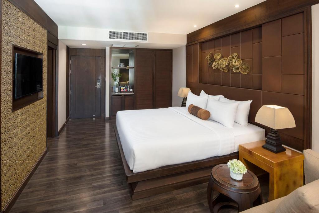 A warmly furnished bedroom with a large bed, television, and built-in storage.