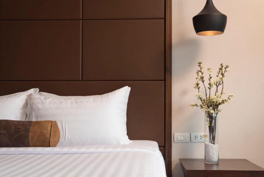 A bed is paired with a bedside table, pendant light, and decorative vase.