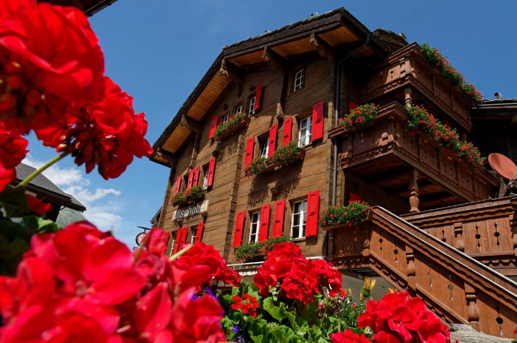 ein Gebäude mit roten Fenstern und Blumen davor in der Unterkunft Hotel Walliserkanne in Grächen