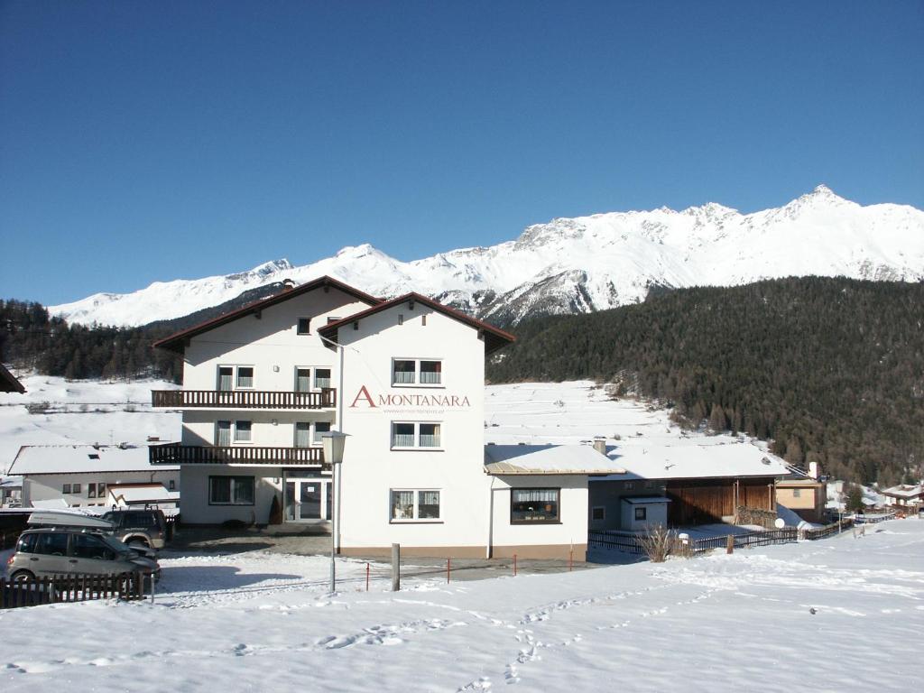a large white building in the snow with snow covered mountains at Amontanara in Nauders