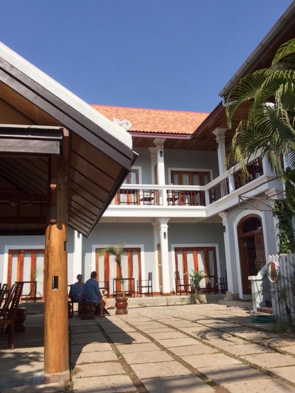 two people sitting in front of a building at Pongkham Residence in Luang Prabang