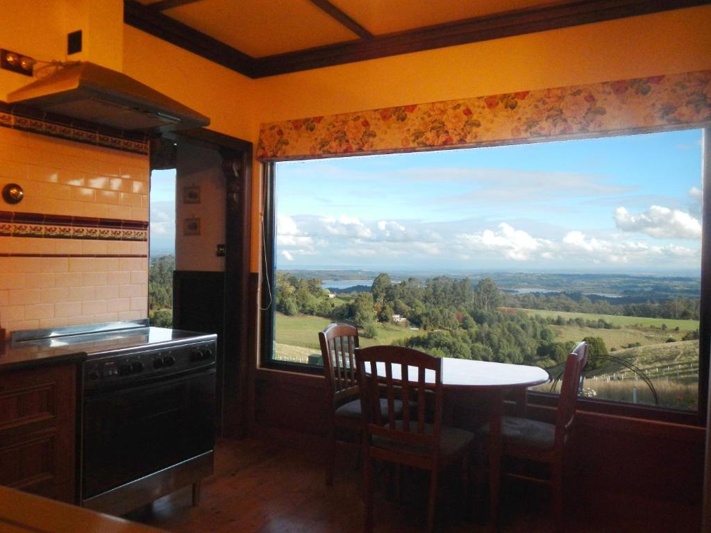 a kitchen with a table and a large window at A Cottage with a View at Tudor Ridge in Kallista