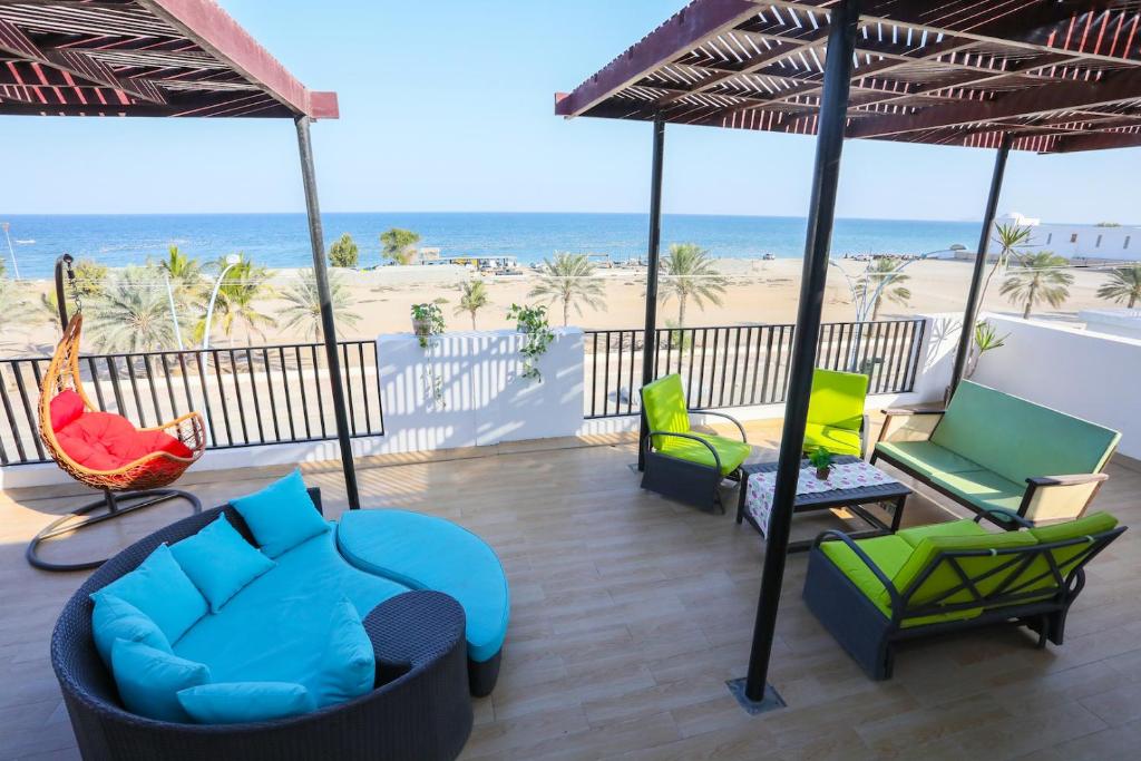 a patio with chairs and umbrellas and the beach at Lana Villa in Muscat