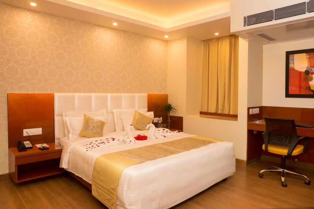 a hotel room with a large bed and a desk at Amalfi Grand in Patna