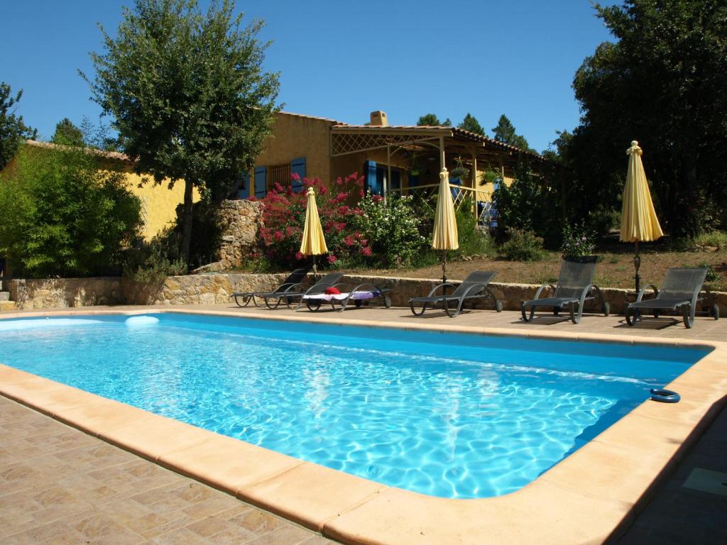 une piscine avec chaises et parasols devant une maison dans l'établissement Villa Thocha, à Montauroux