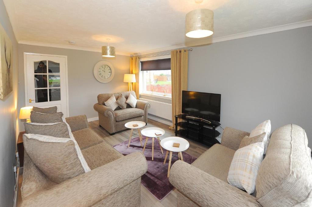 a living room with a couch and a tv at Spacious 3 bedroom house in Stirling