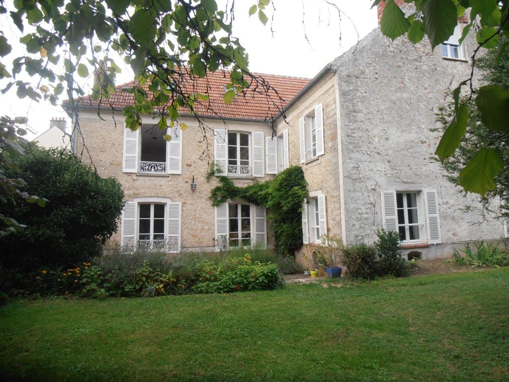 a large stone house with white windows and a yard at La Fruitiere in Saints