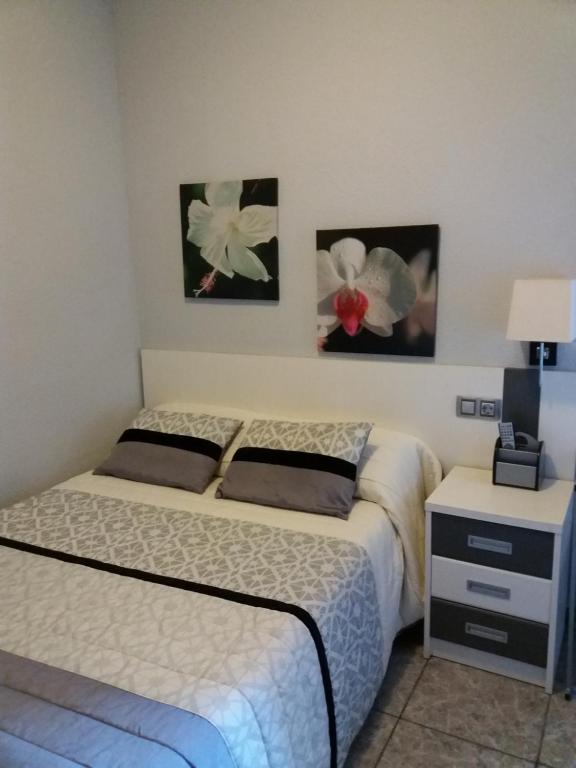 a bedroom with a bed and two pictures on the wall at Hostal La Pilarica in Paterna