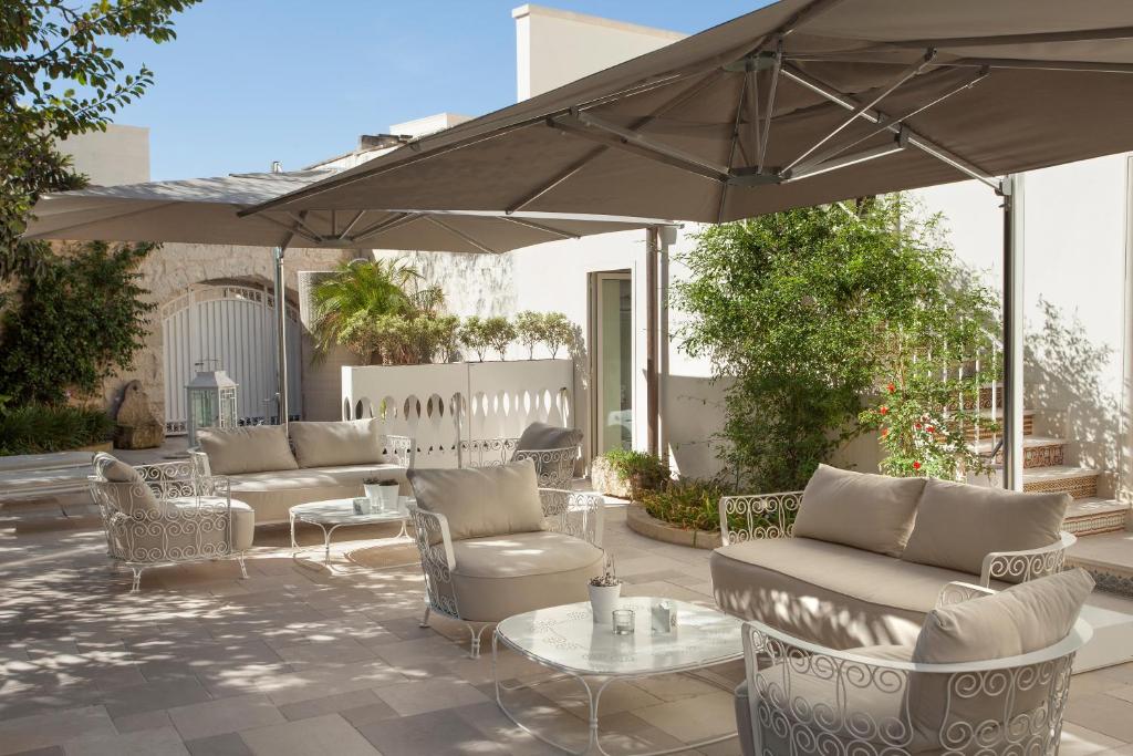 un patio con sofás, mesas y una sombrilla en Mantatelurè en Lecce