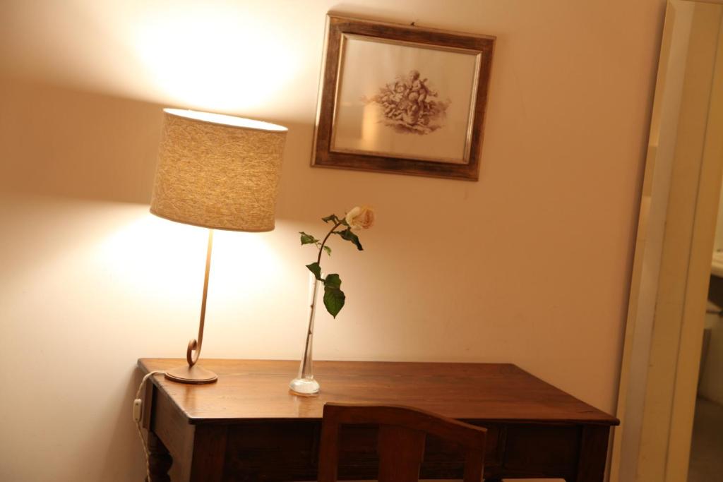 a desk with a lamp and a flower on it at B&B Casa Ruffino in Balestrate