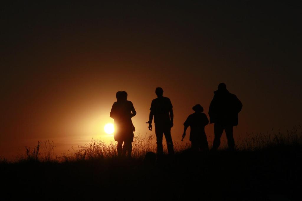 eine Gruppe von Menschen, die bei Sonnenuntergang auf einem Feld stehen in der Unterkunft Ferienwohnungen Tietgen in Katharinenhof