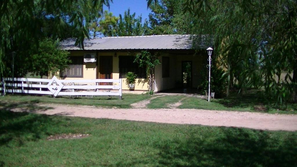 una pequeña casa con una cerca blanca delante de ella en Posada del Campo en San José