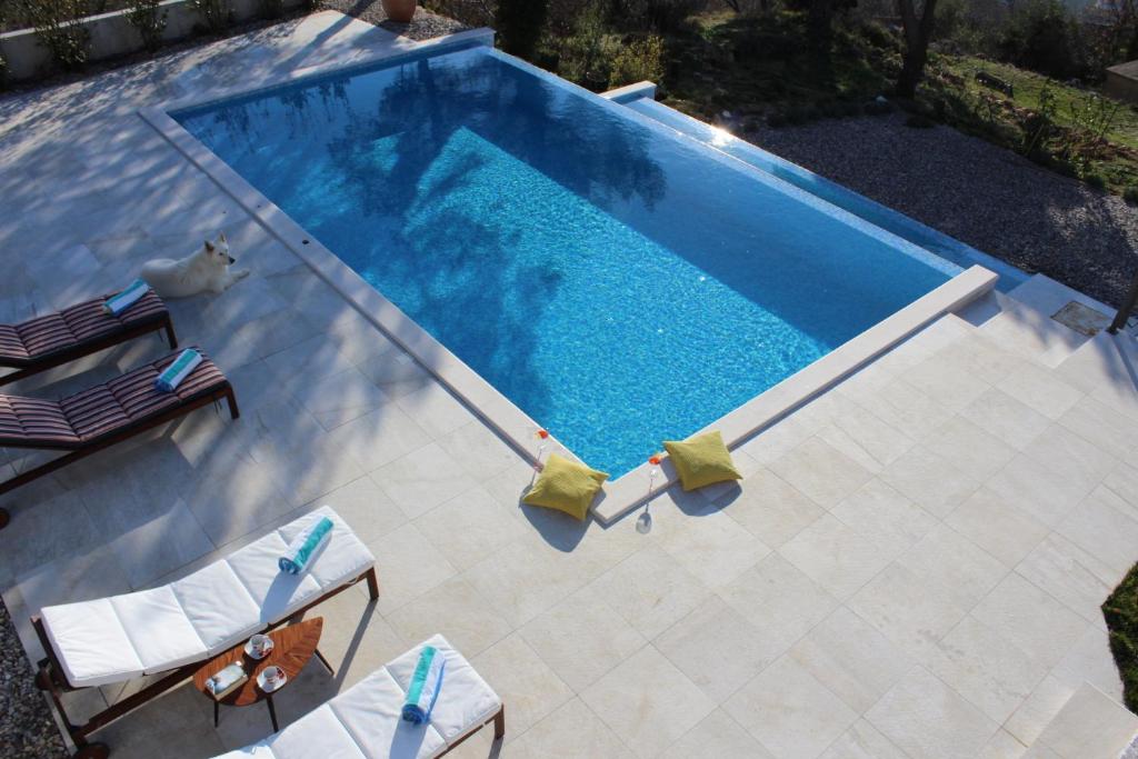 an overhead view of a swimming pool with two lawn chairs at Villa Yanko, free parking, heated pool, sea view, own children's playground, excellent facilities in Tučepi