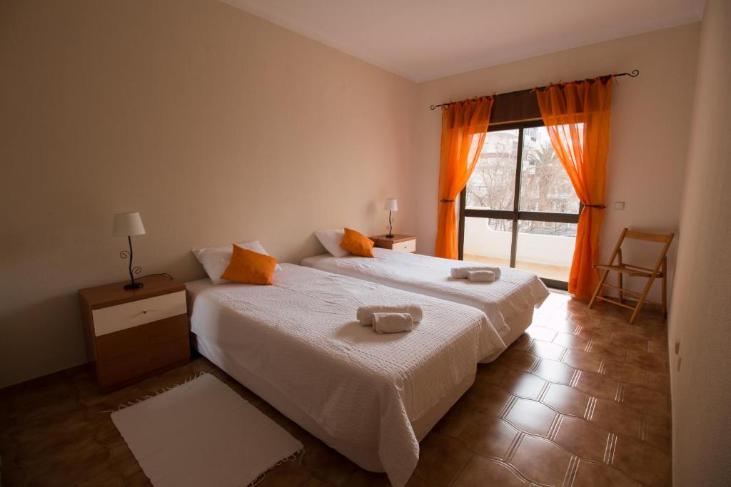 ラゴスにあるPerfect Loc Apartment Lagos 3 bedroom/2bthのベッドルーム1室(ベッド2台付)、窓(オレンジ色のカーテン付)