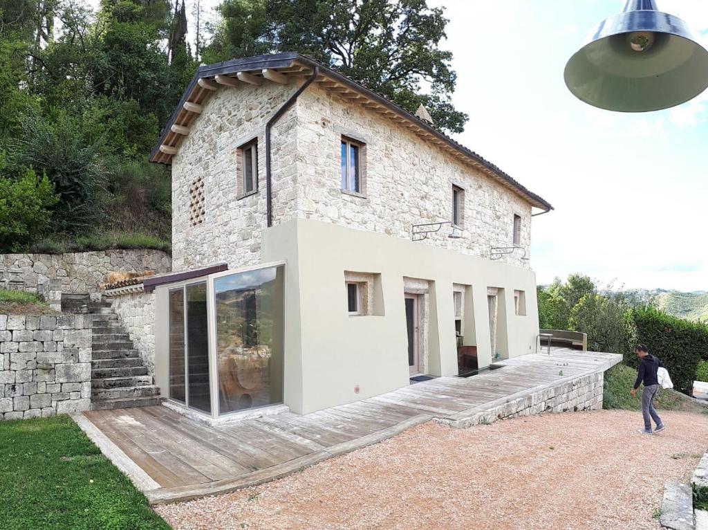 een stenen huis met een persoon die ervoor loopt bij Villa Fortezza Antique Rooms in Ascoli Piceno