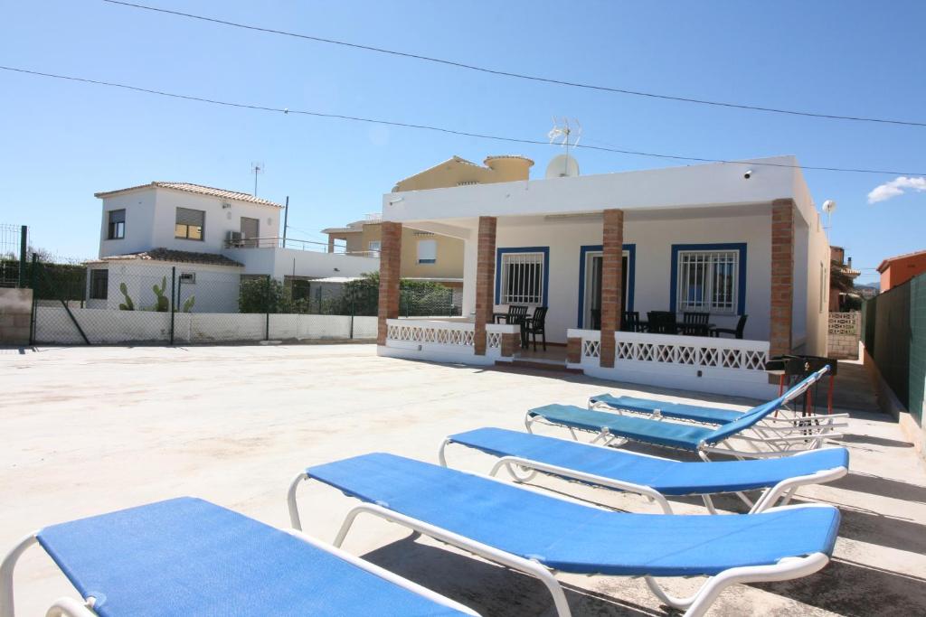 four blue lounge chairs in front of a building at OLIVA HOLIDAYS 4 in Oliva