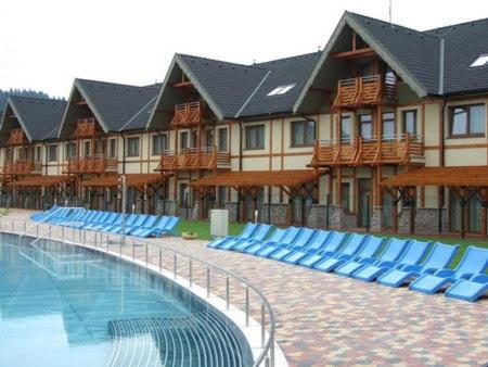 a resort with blue lounge chairs and a swimming pool at Wellness Hotel Bešeňová in Bešeňová