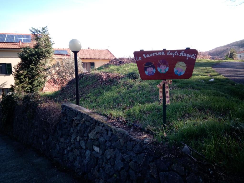 ein Schild im Gras neben einer Steinmauer in der Unterkunft B&B la taverna degli Angeli in Vezzi Portio