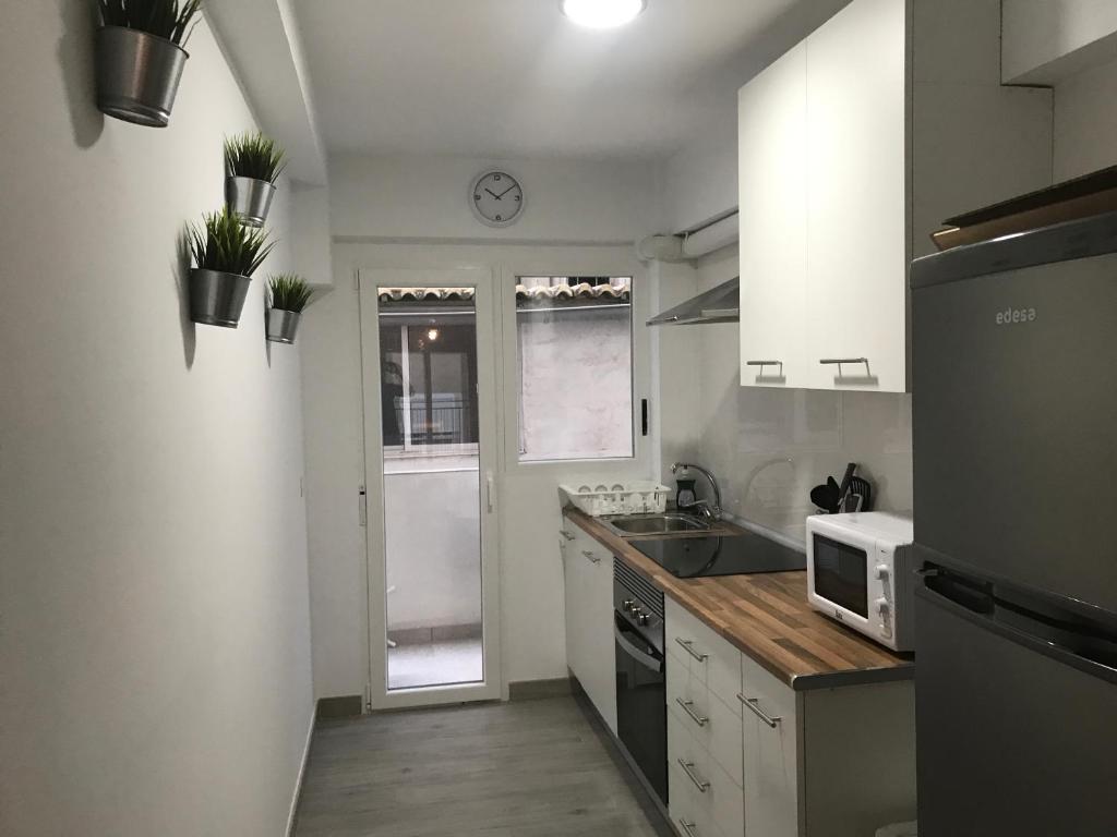 eine kleine Küche mit einer Spüle und einer Mikrowelle in der Unterkunft Playa Precioso apartamento para familia con niños in San Juan de Alicante