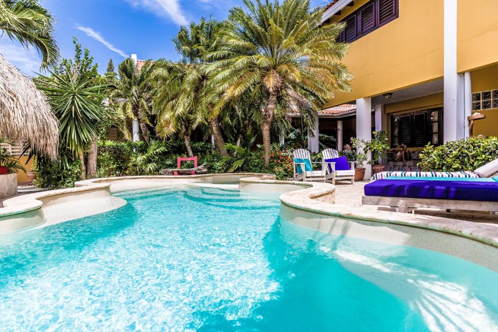 a swimming pool with blue chairs and palm trees at Ocean View Villas in Kralendijk