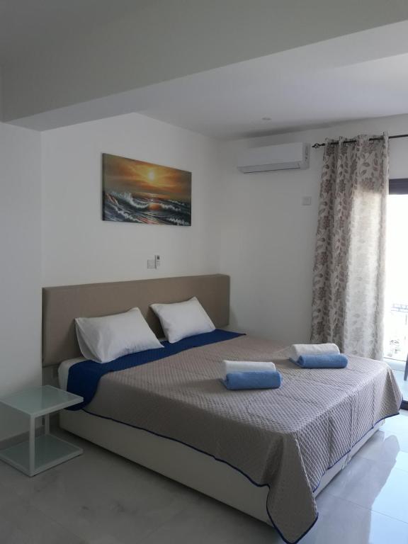 a bedroom with a large bed with blue pillows at P.L Hermes Studios & Apartments in Larnaka