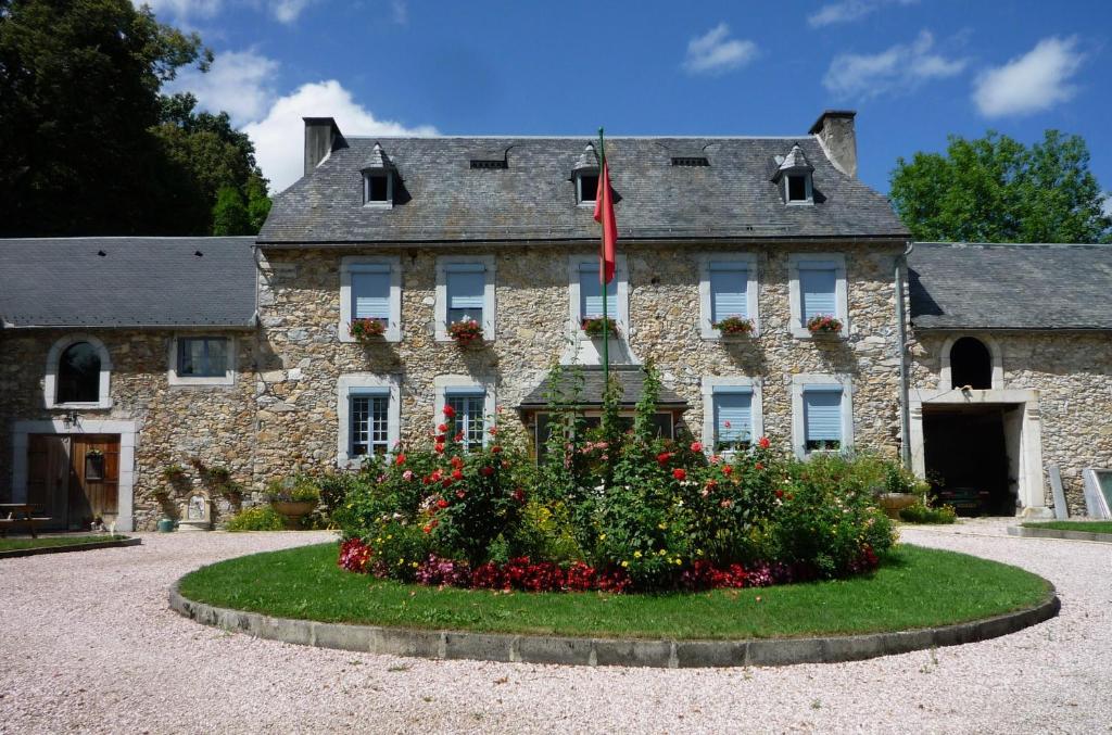 an old stone house with a flower garden in front of it at Domaine Véga in Saint-Arroman