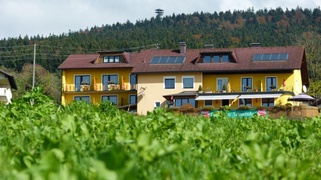una casa gialla con una piscina di fronte di Gasthaus - Pension Sonnenhof a Ulrichsberg