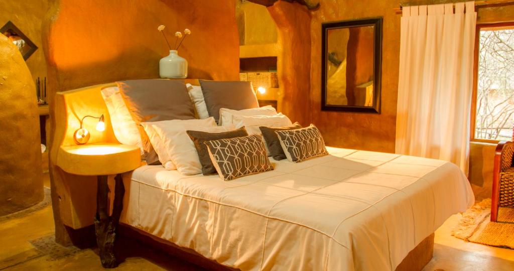 1 dormitorio con 1 cama con sábanas y almohadas blancas en Little Bush Lodge, en Hoedspruit