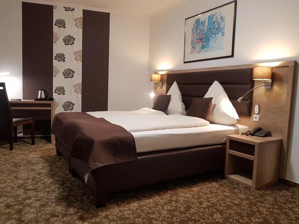 バート・ツヴィッシェンアーンにあるPark Hotelの大きなベッドとデスクが備わるホテルルームです。