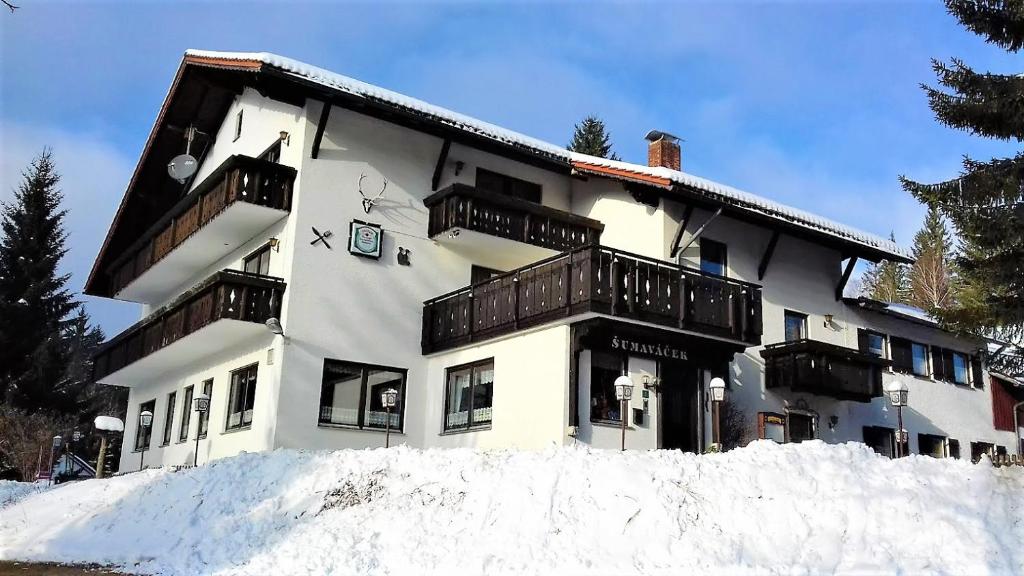 a building with snow in front of it at Penzion Sumavacek in Bayerisch Eisenstein