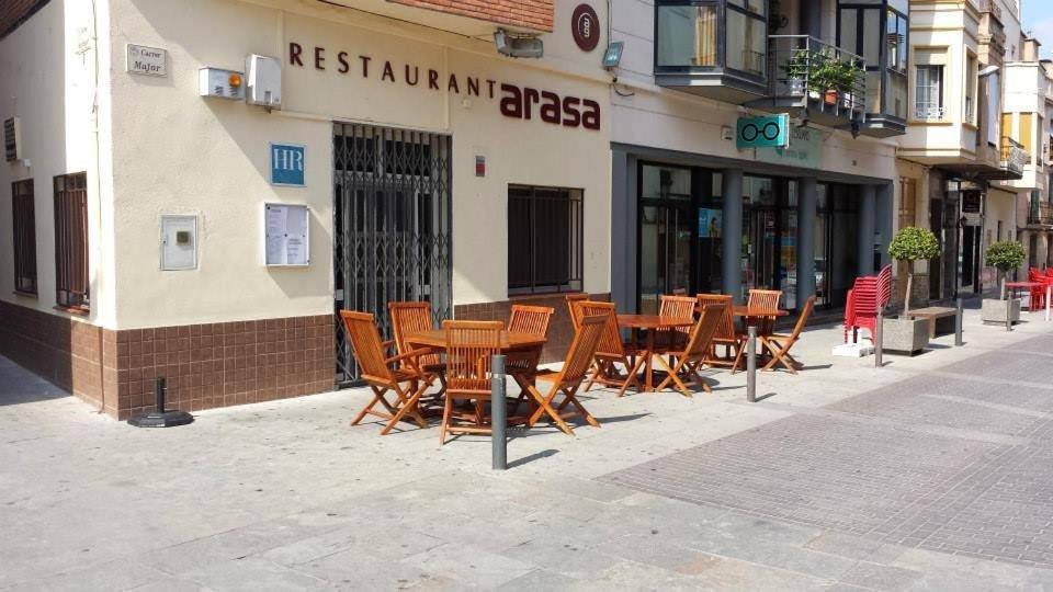 Hostal Restaurante Arasa في سانتا باربارا: مجموعة طاولات وكراسي خشبية خارج المطعم