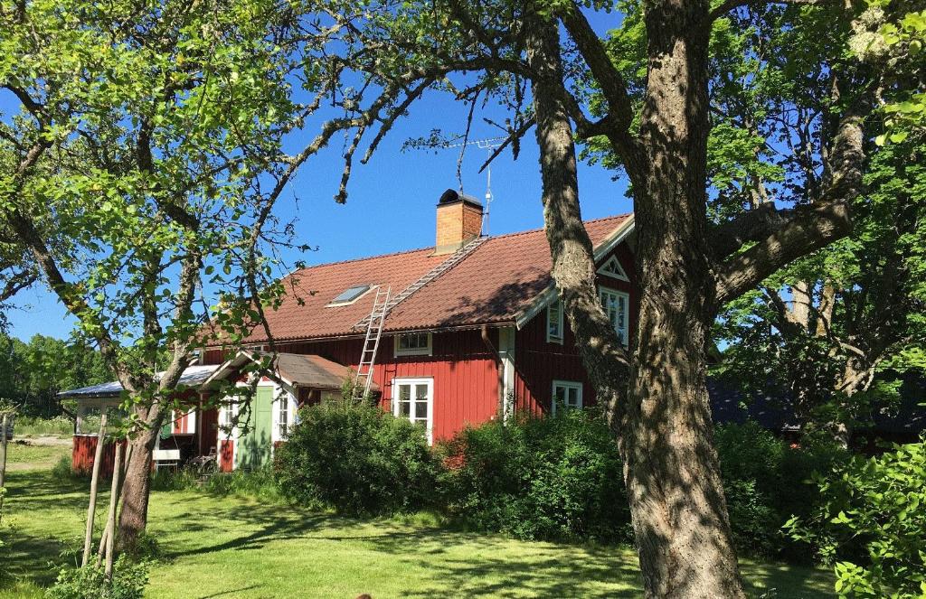 una casa roja con árboles delante de ella en Sättraby villa en Norrtälje