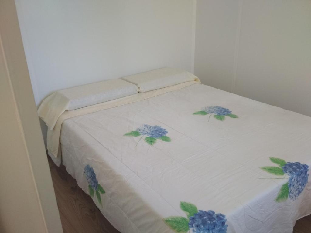 Una cama blanca con flores azules. en Limón y Sal, en Ciudad de la Costa