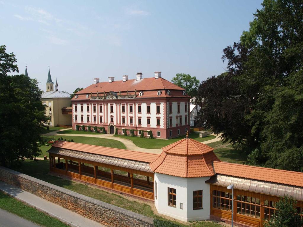 a large building with a red roof in front of it at Zámecké ubytování U dobré hraběnky in Kunín