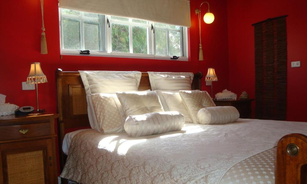 a bedroom with red walls and a bed with white pillows at Lanterns Retreats in Dunsborough