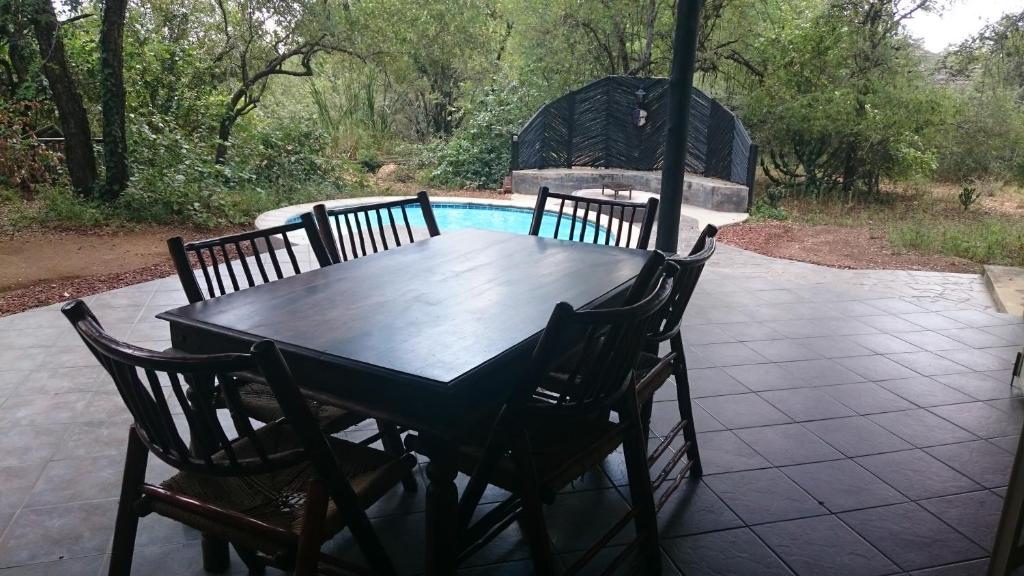einen Holztisch und Stühle auf einer Terrasse in der Unterkunft Kruger River Villas - Mtombo in Marloth Park
