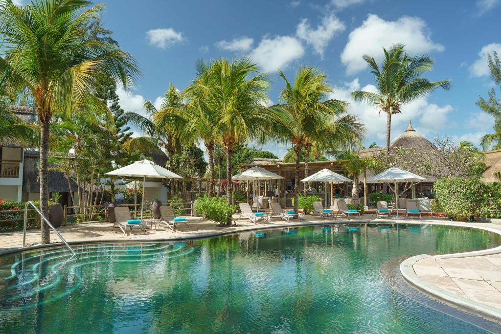勒拉芒丹的住宿－考恩沼澤地酒店，棕榈树和椅子的度假村的游泳池