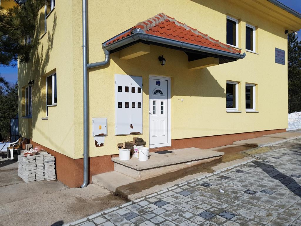 mały żółty dom z białymi drzwiami w obiekcie Apartment Oaza Mira w mieście Divčibare