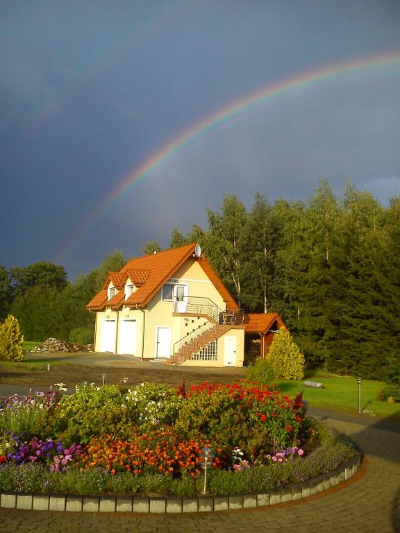 a rainbow over a house with a garden and flowers at Agroturystyka Düsselkamp Tumiany in Barczewo