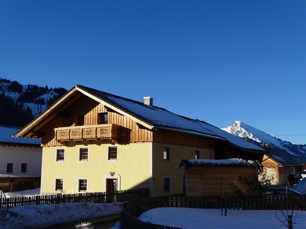 una casa nella neve con una montagna sullo sfondo di Ferienhaus Carmen a Grän